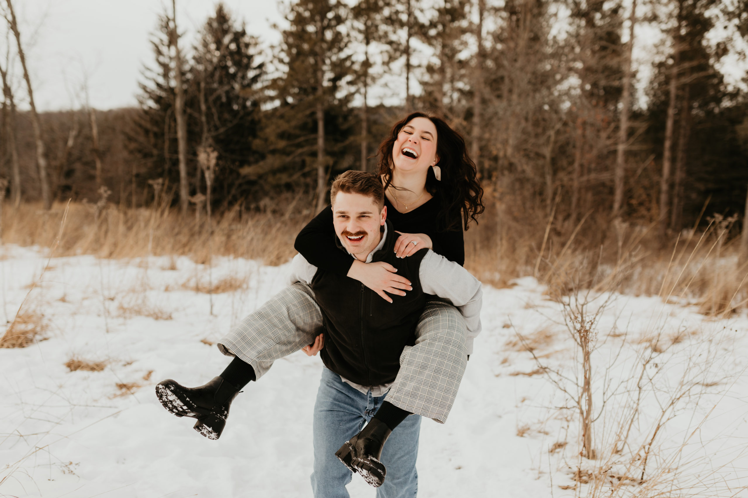 Couple laughing during piggy back ride in the snow
