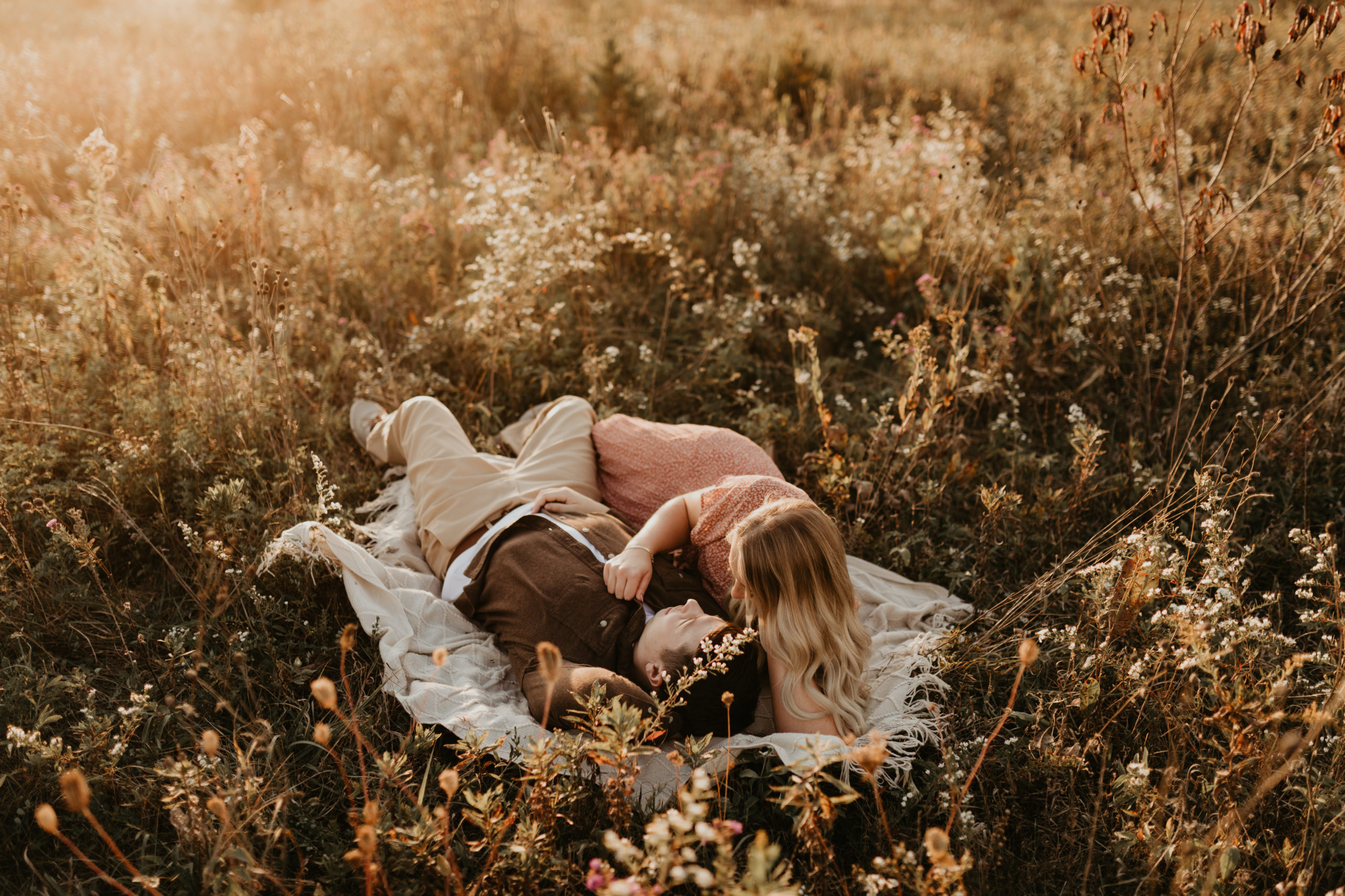 couple laying in golden grass during sunset