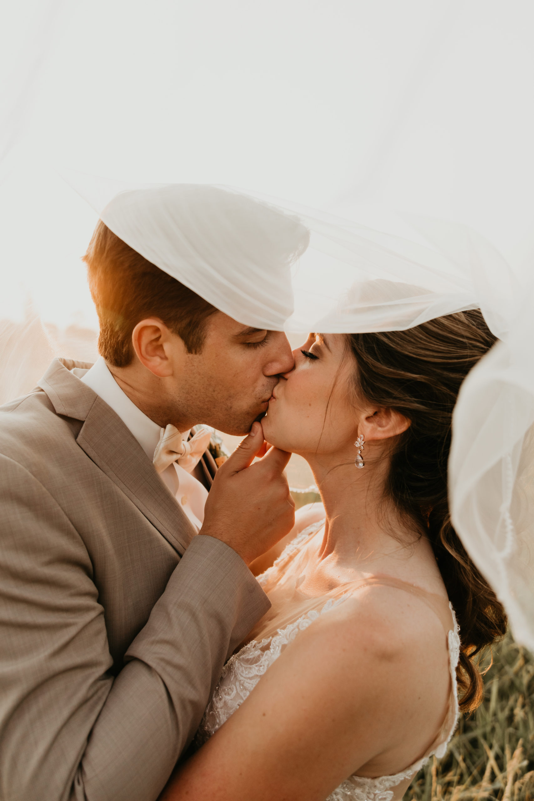 couple kissing under veil at sunset